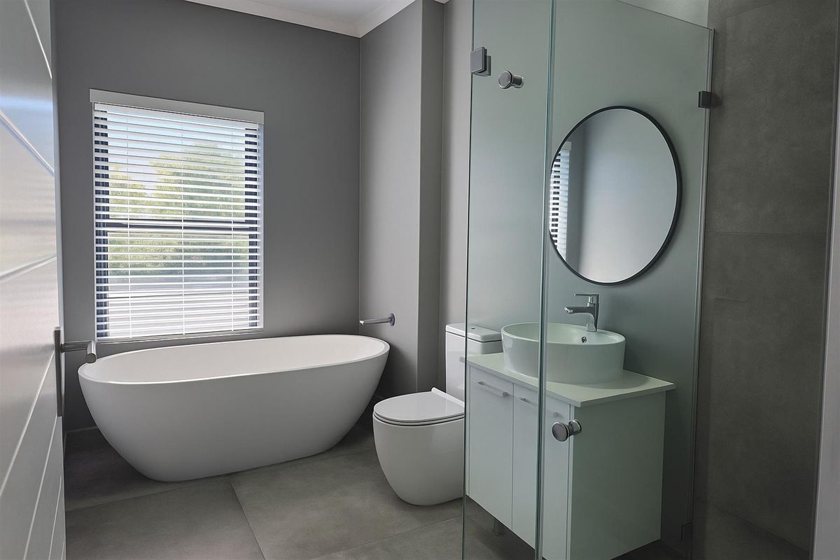 Modern bathroom featuring a freestanding bathtub, a glass-enclosed shower, a vanity with a vessel sink, and contemporary grey floor tiles.