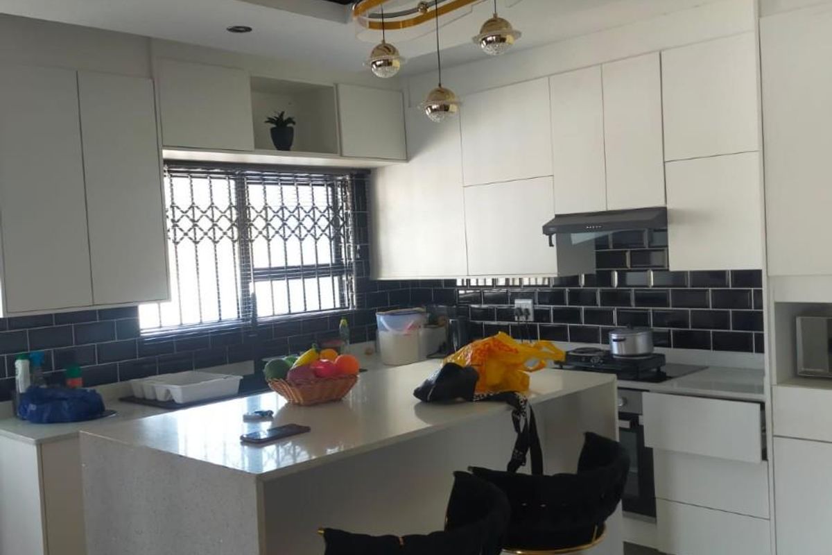 Modern kitchen featuring white cabinetry, a central island with stone countertops, black subway tile backsplash, and integrated extractor fan.