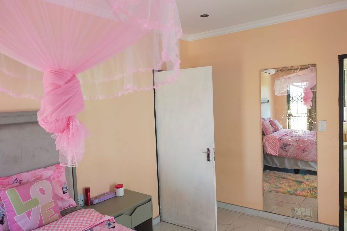 A bedroom featuring tiled flooring, recessed downlighting, and a large wall-mounted mirror.