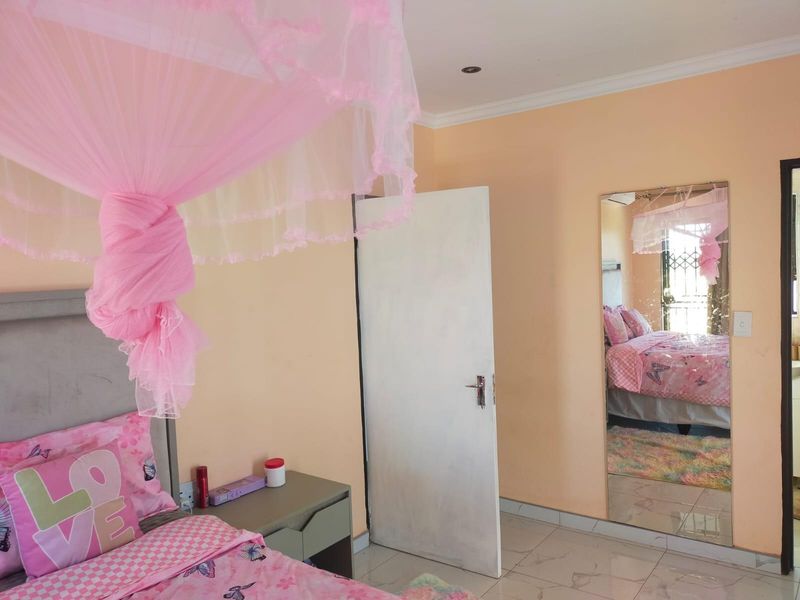 A bedroom featuring tiled flooring, recessed downlighting, and a large wall-mounted mirror.