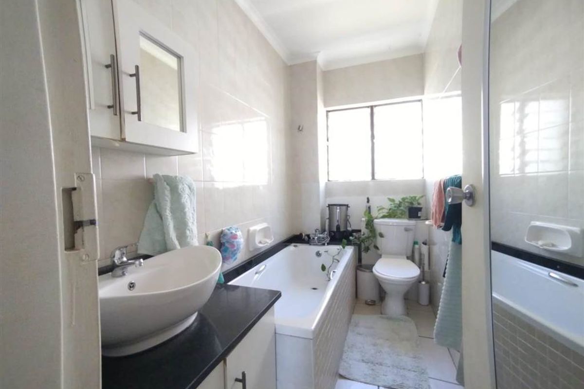 A functional bathroom featuring a vessel sink on a vanity cabinet, a bathtub, and a toilet with tiled walls and flooring.