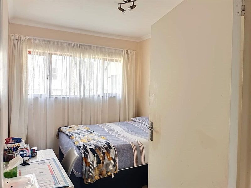 A functional bedroom featuring a window with curtains and a ceiling-mounted spotlight fixture.