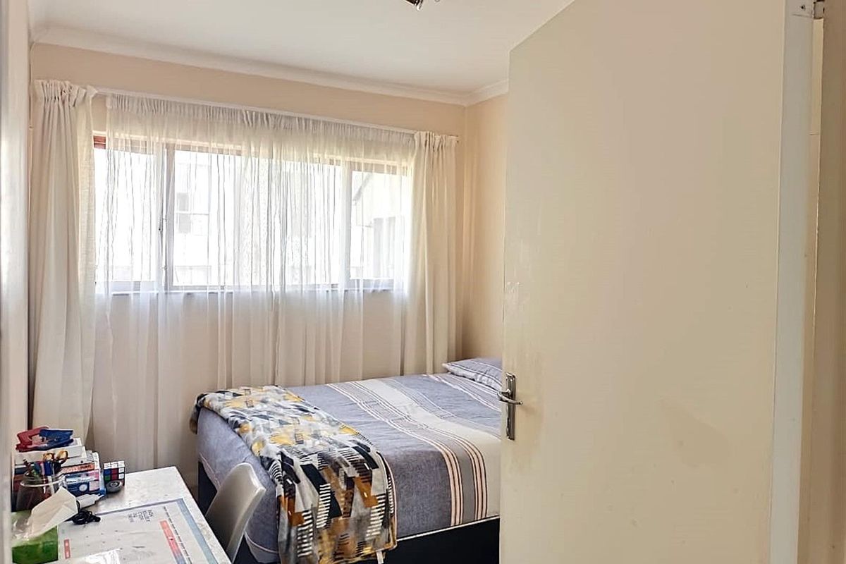 A functional bedroom featuring a window with curtains and a ceiling-mounted spotlight fixture.