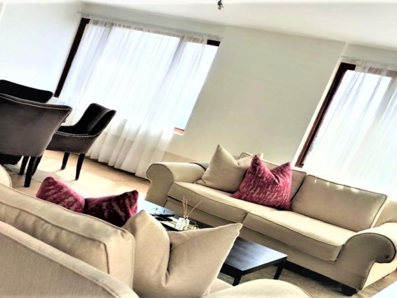 A bright and spacious open-plan living and dining area featuring large windows that allow for ample natural light.