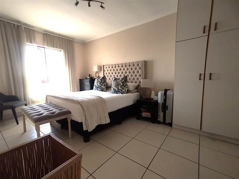 A well-lit bedroom featuring tiled flooring, built-in cupboards, and a sliding door providing access to natural light.