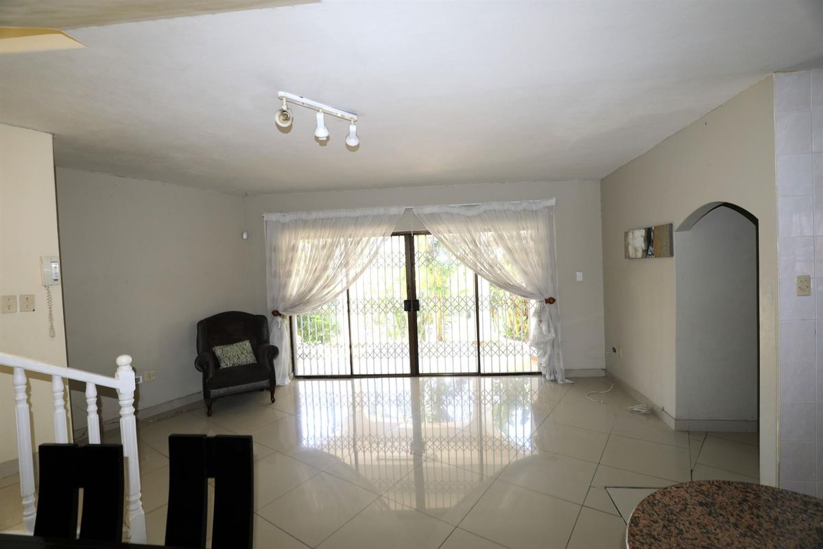 Spacious living area featuring large sliding glass doors with security gates, tiled flooring, and direct access to the outdoor space.