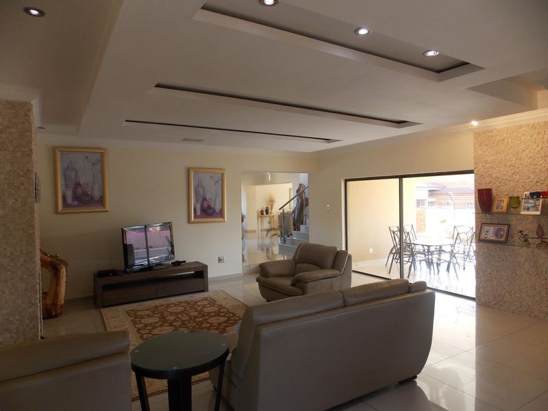 Spacious open-plan living area featuring recessed ceiling lighting, tiled flooring, and large sliding glass doors providing seamless access to the outdoor patio.