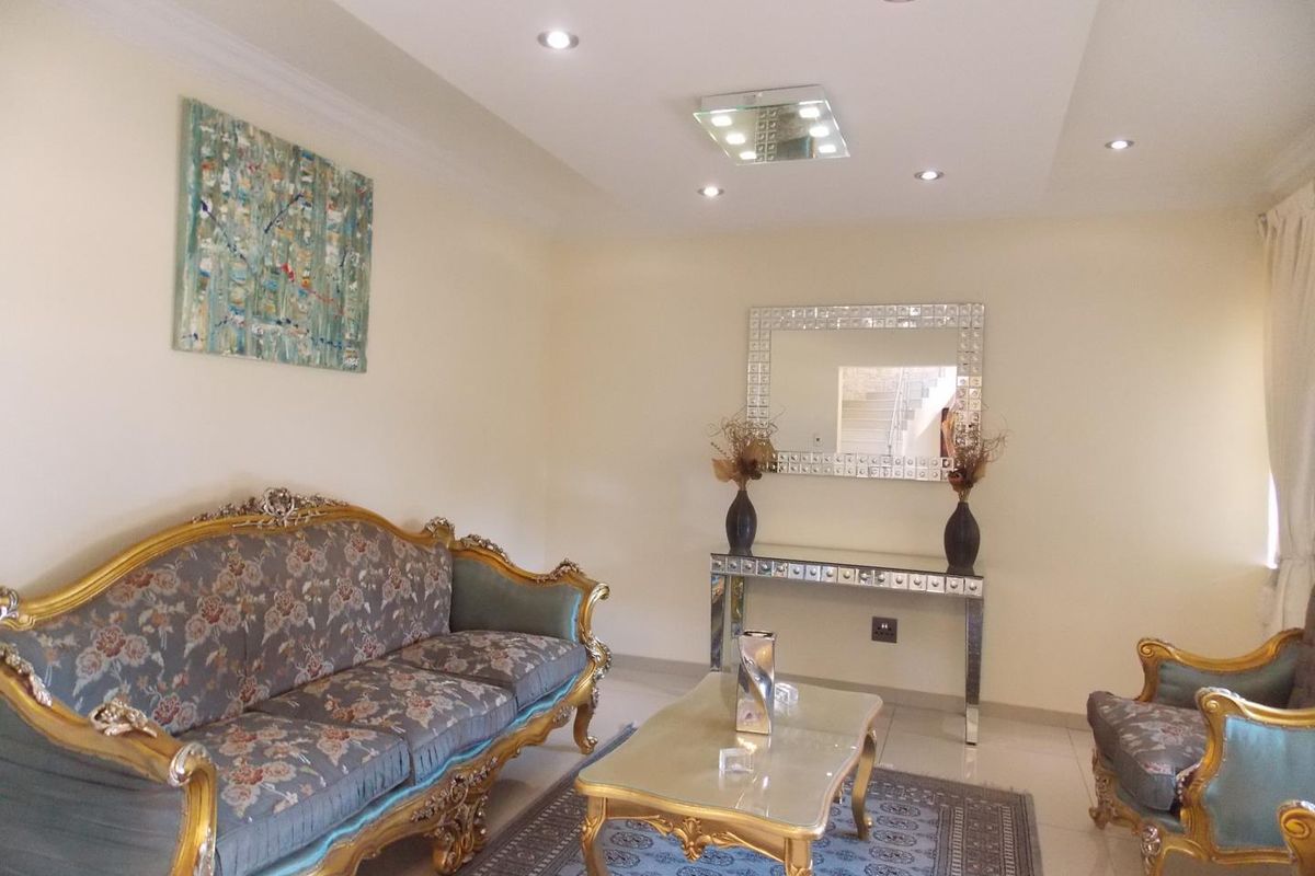 A well-maintained living room featuring recessed ceiling lighting, a modern tray ceiling design, and polished floor tiles.
