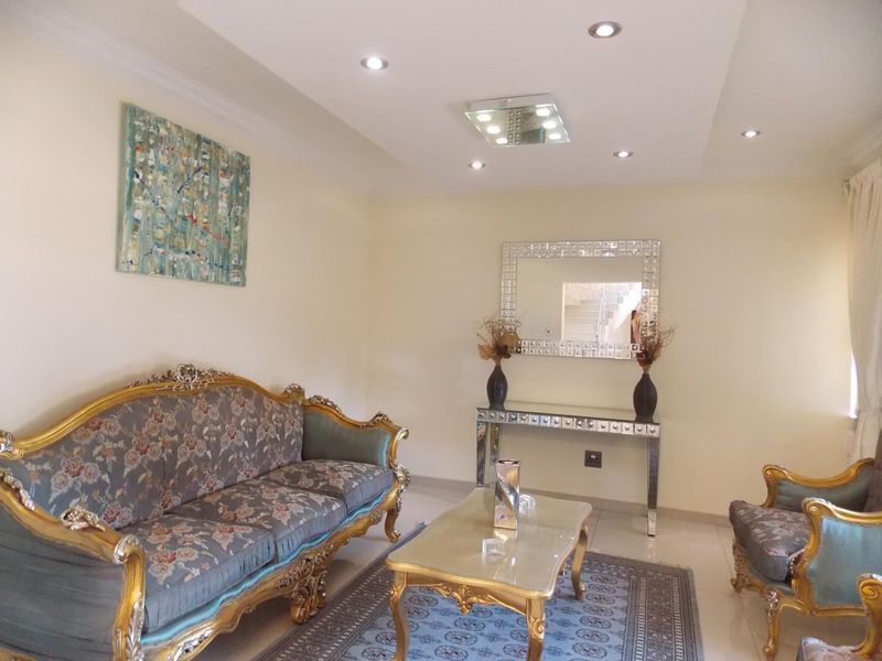 A well-maintained living room featuring recessed ceiling lighting, a modern tray ceiling design, and polished floor tiles.