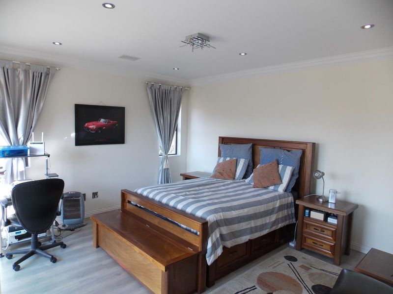 A spacious bedroom featuring recessed ceiling lighting, crown molding, and light-toned wood-look flooring.