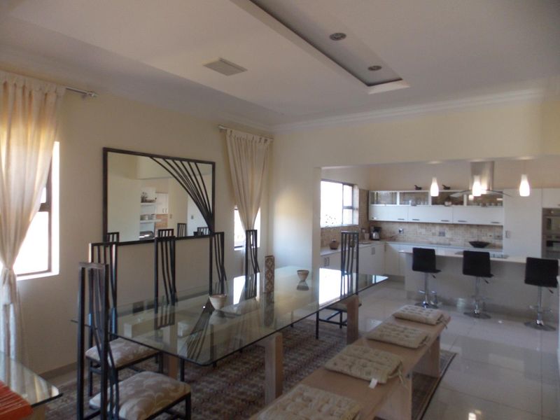 Open-plan living and dining area featuring a modern kitchen with breakfast bar, sleek cabinetry, and integrated lighting.