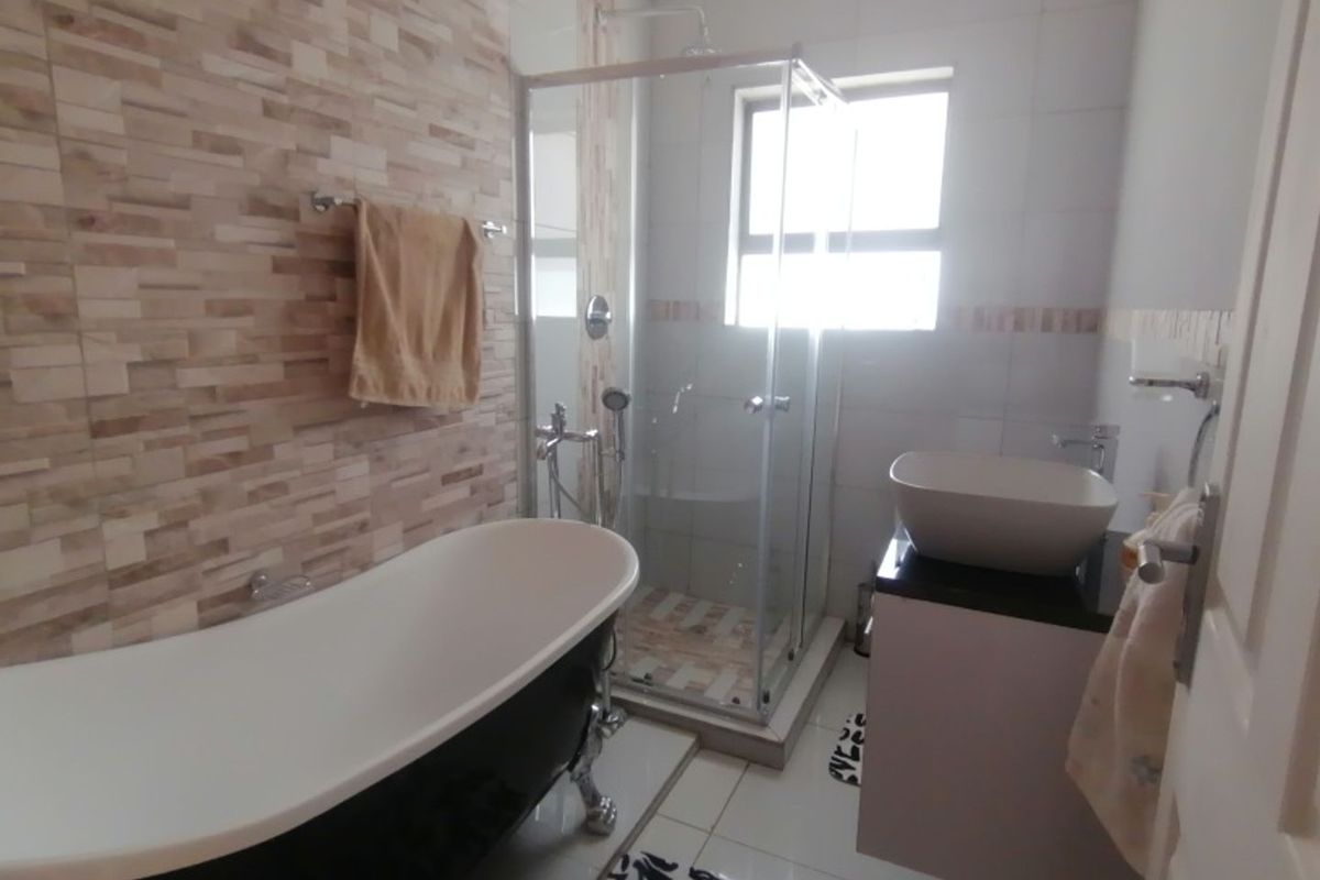 Modern bathroom featuring a freestanding bathtub, a glass-enclosed shower, and a contemporary vessel sink vanity with tiled wall accents.