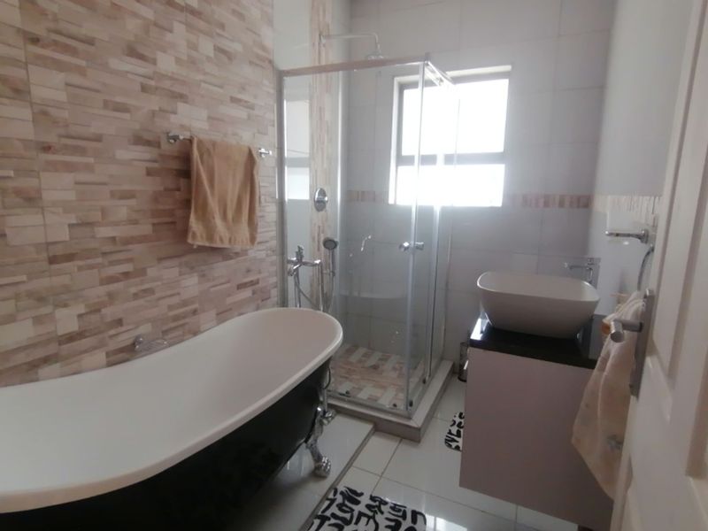 Modern bathroom featuring a freestanding bathtub, a glass-enclosed shower, and a contemporary vessel sink vanity with tiled wall accents.