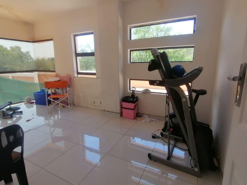 A multi-purpose room featuring large windows, tiled flooring, and neutral walls, currently utilized as a flexible space with natural light.