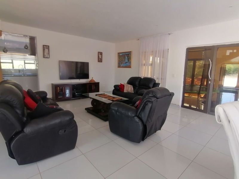 Spacious open-plan living area featuring neutral tiled flooring, large glass sliding doors providing natural light, and a seamless flow to the adjacent kitchen space.