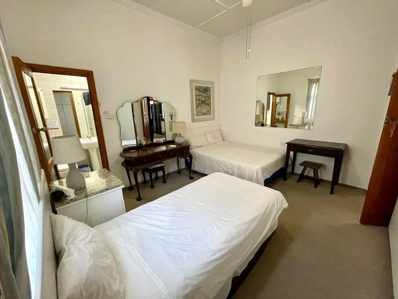 A spacious bedroom featuring high ceilings with decorative cornicing, neutral wall finishes, and direct access to an en-suite bathroom.