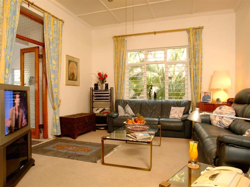 A comfortable living room featuring large louvre windows, coved ceilings, and classic timber door frames, offering a bright and traditional living space.