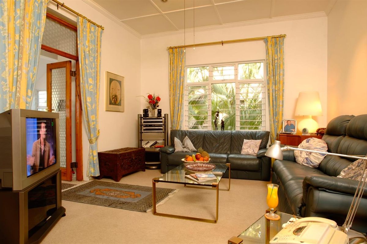 A comfortable living room featuring large louvre windows, coved ceilings, and classic timber door frames, offering a bright and traditional living space.