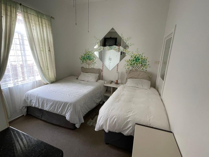 A functional bedroom featuring a window with security bars and a decorative wall-mounted mirror.