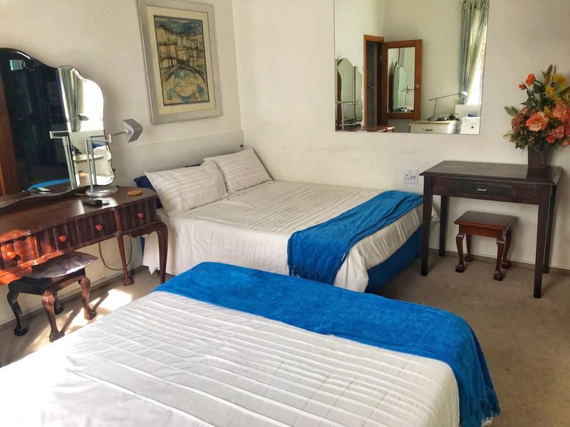 A functional bedroom featuring carpeted flooring and a large wall-mounted mirror, providing a comfortable and practical sleeping space.