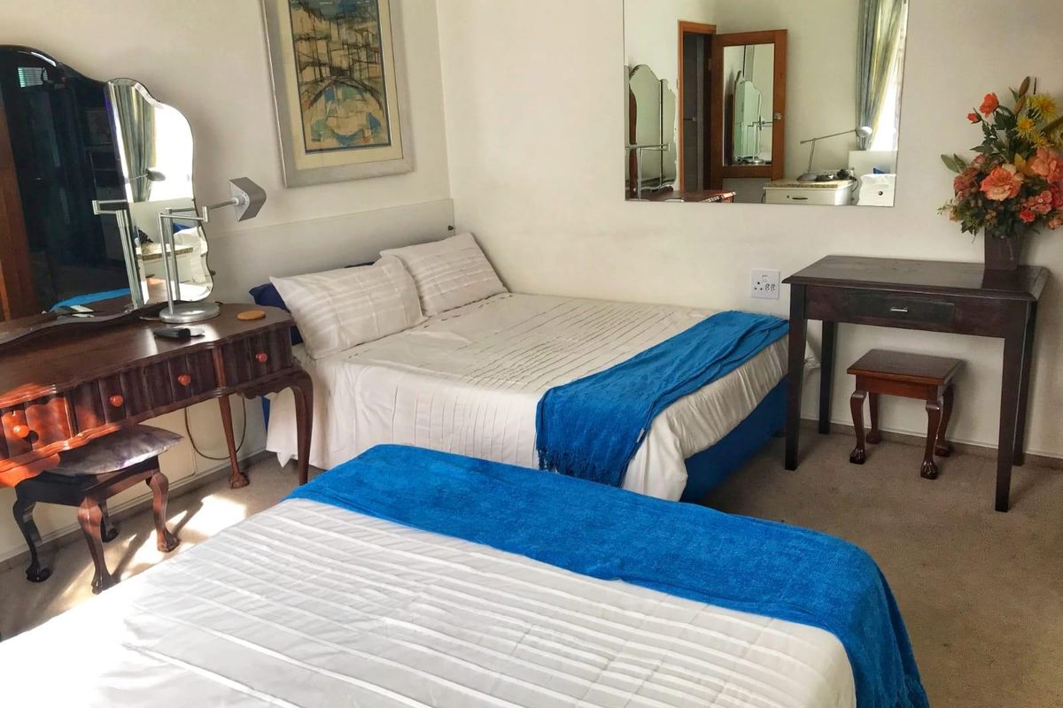 A functional bedroom featuring carpeted flooring and a large wall-mounted mirror, providing a comfortable and practical sleeping space.
