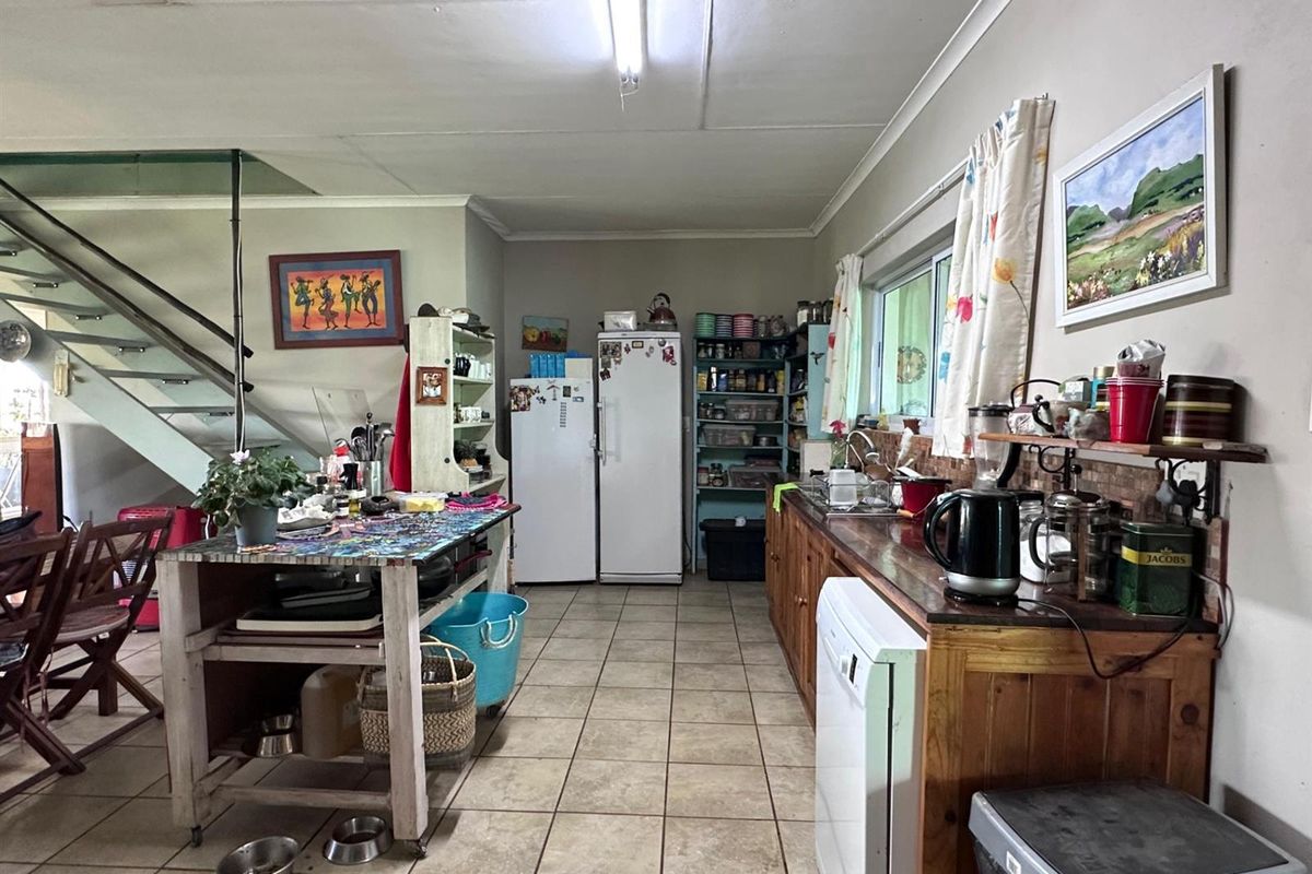 A functional kitchen area featuring wooden cabinetry, tiled flooring, and an integrated staircase, offering a practical layout with potential for cosmetic updates.