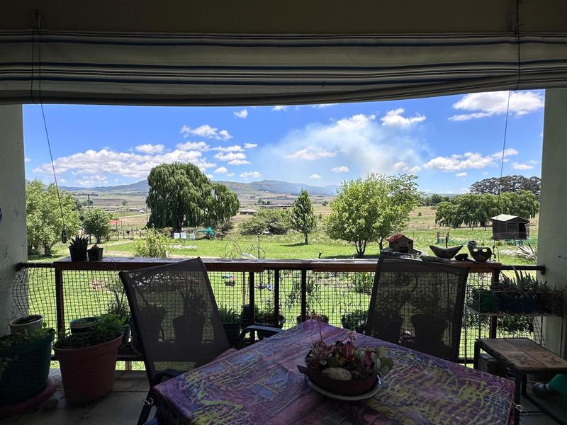 Covered patio area featuring a protective railing and retractable awning, offering expansive views over the surrounding small holding landscape.