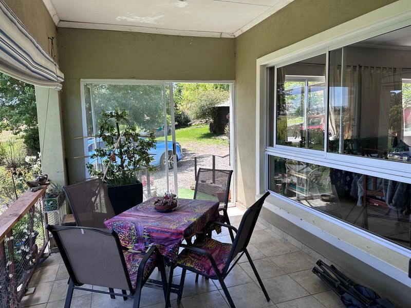 A covered patio area featuring tiled flooring and large sliding glass doors, providing a seamless transition to the outdoor garden space.