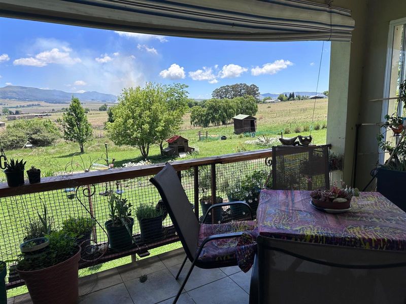 Covered patio area featuring a retractable awning, tiled flooring, and a wire mesh balustrade with scenic views over the small holding.