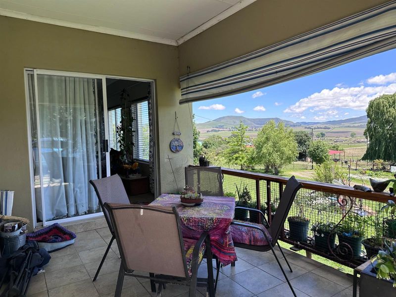 Covered patio featuring tiled flooring, a retractable awning, and sliding door access, offering expansive views of the surrounding landscape.