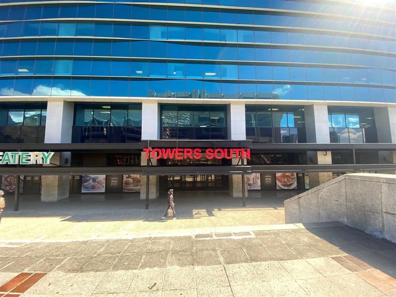 Front elevation of the Towers South office building featuring a modern glass facade, paved entrance plaza, and covered walkway.