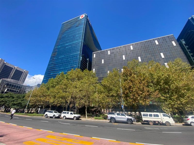 A modern high-rise office building featuring a prominent glass facade and contemporary architectural design, situated along a main street.