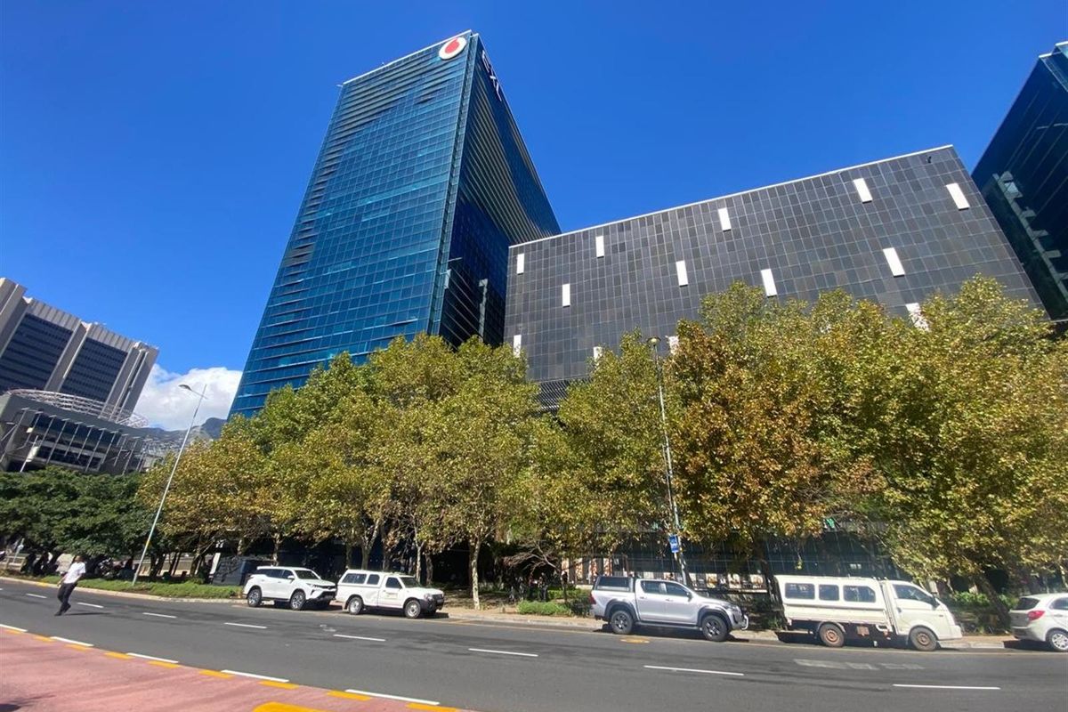 A modern high-rise office building featuring a prominent glass facade and contemporary architectural design, situated along a main street.