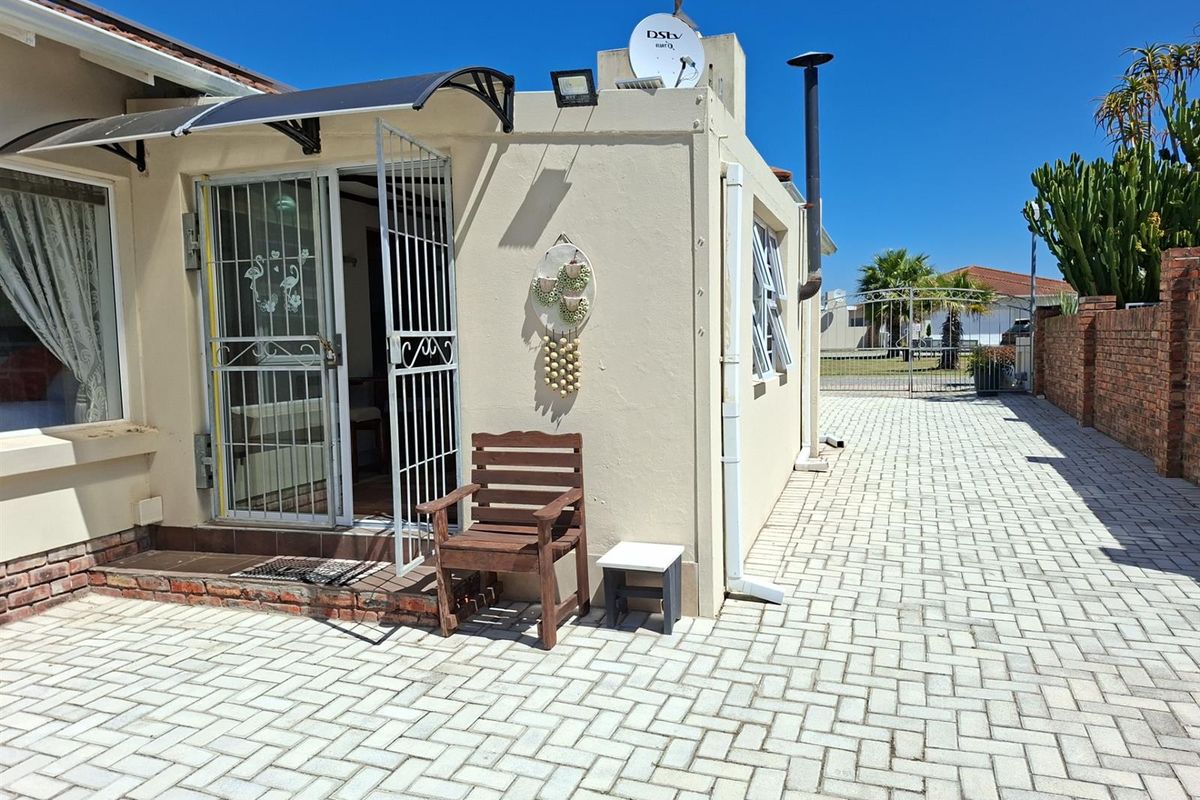 Exterior view of the townhouse featuring paved driveway, security gate, satellite dish, and external chimney stack.