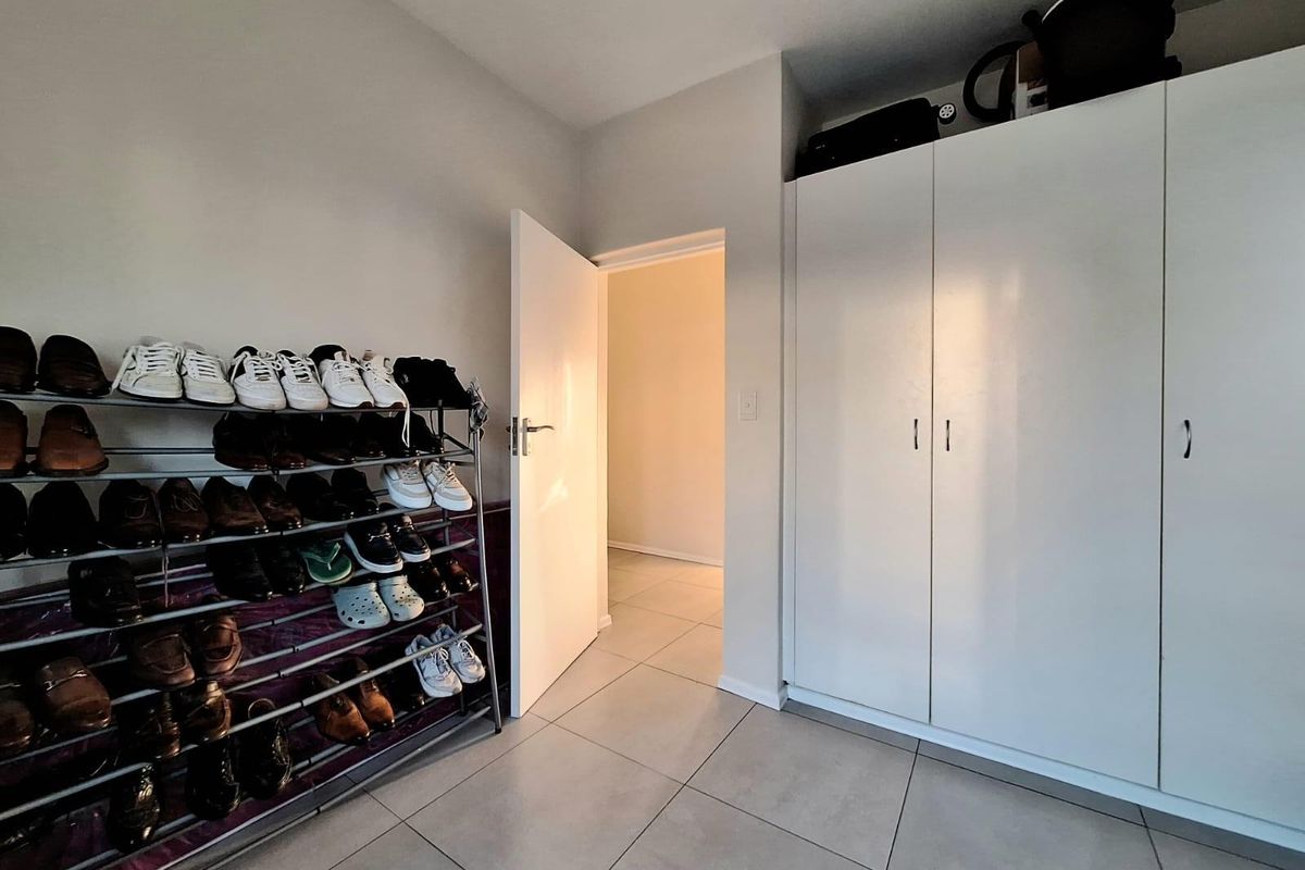 A bedroom featuring neutral tiled flooring and white built-in cupboards, providing ample storage space and a clean, functional layout.