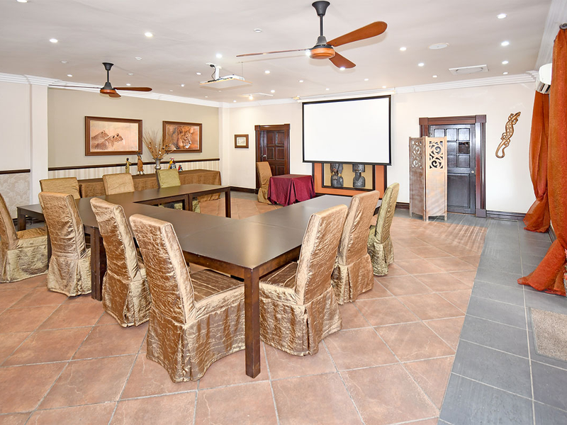 Spacious lodge living area featuring tiled flooring, recessed lighting, ceiling fans, and a built-in projector screen, suitable for meetings or events.