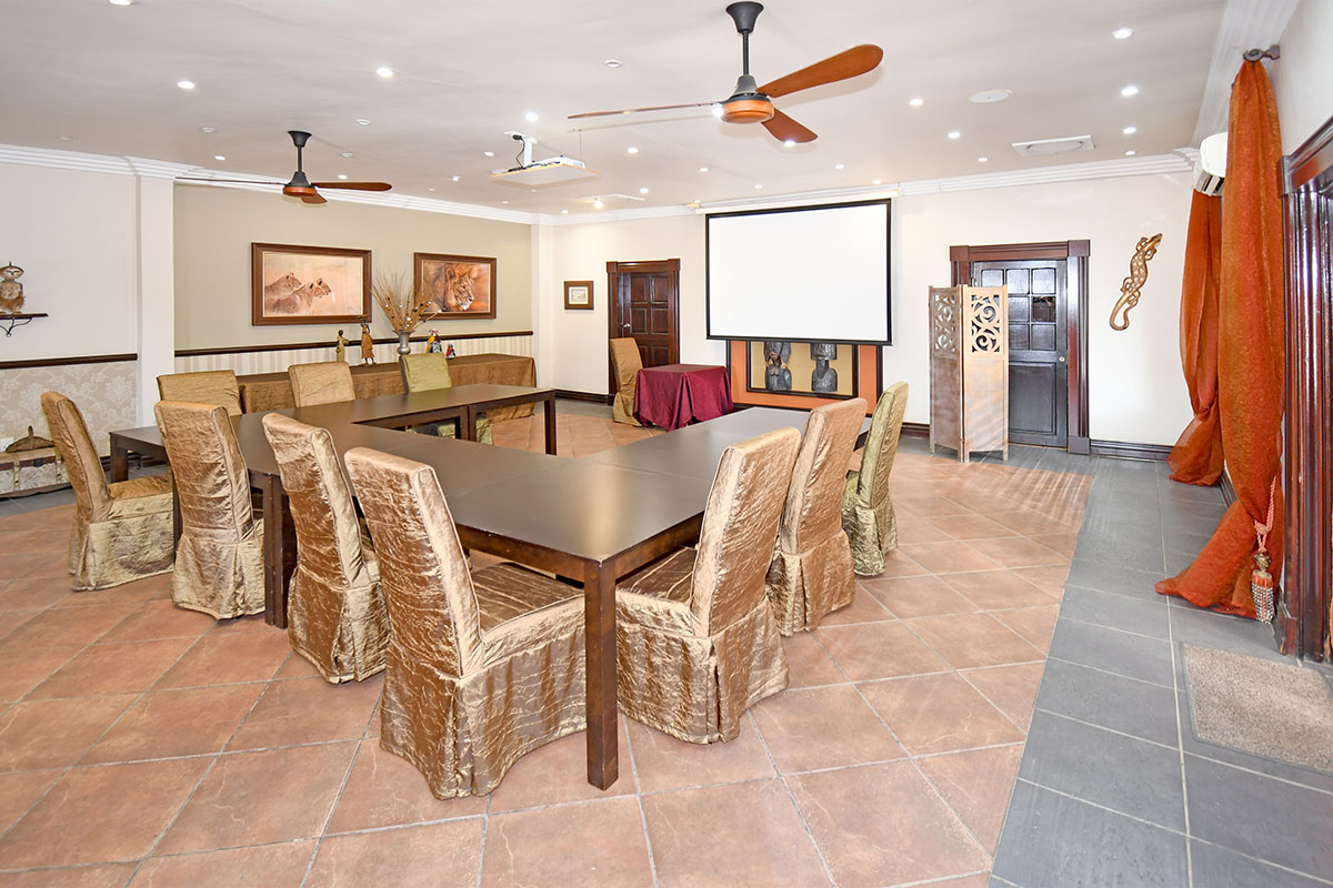 Spacious lodge living area featuring tiled flooring, recessed lighting, ceiling fans, and a built-in projector screen, suitable for meetings or events.