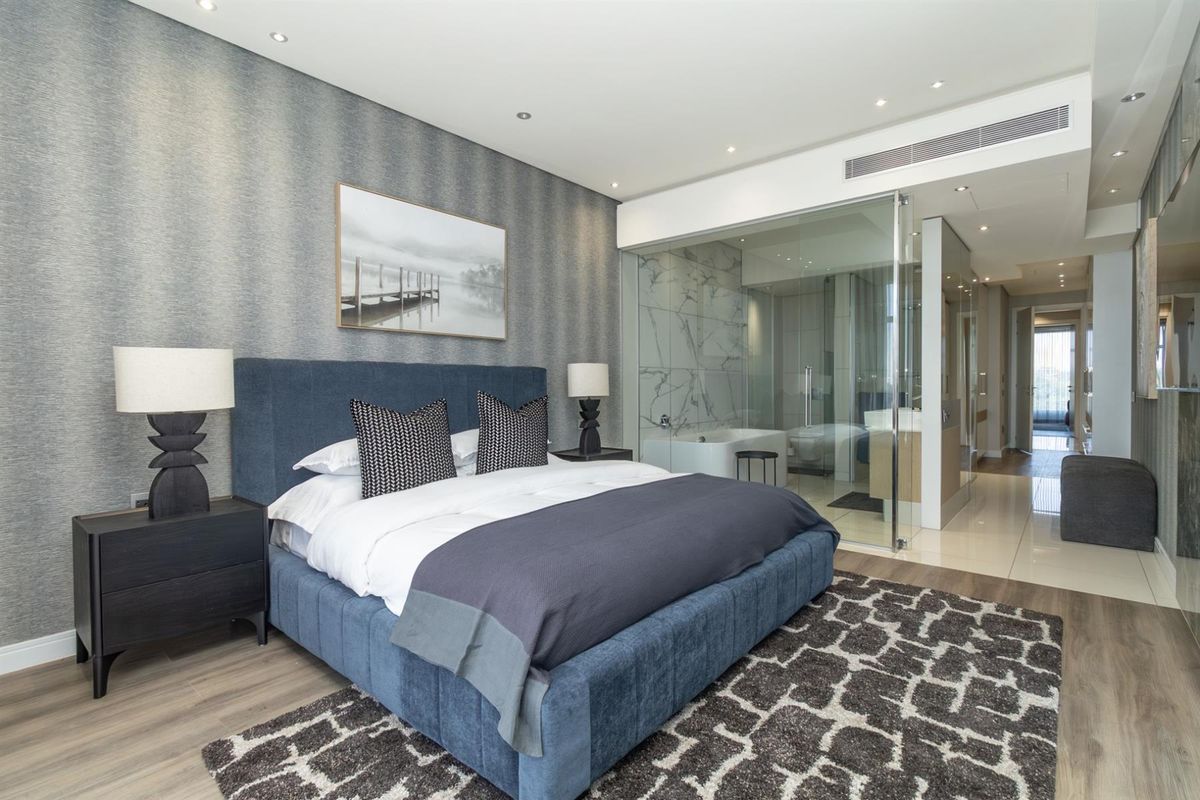 Modern bedroom featuring an en-suite bathroom with glass partitioning, recessed ceiling lighting, and high-quality finishes throughout.