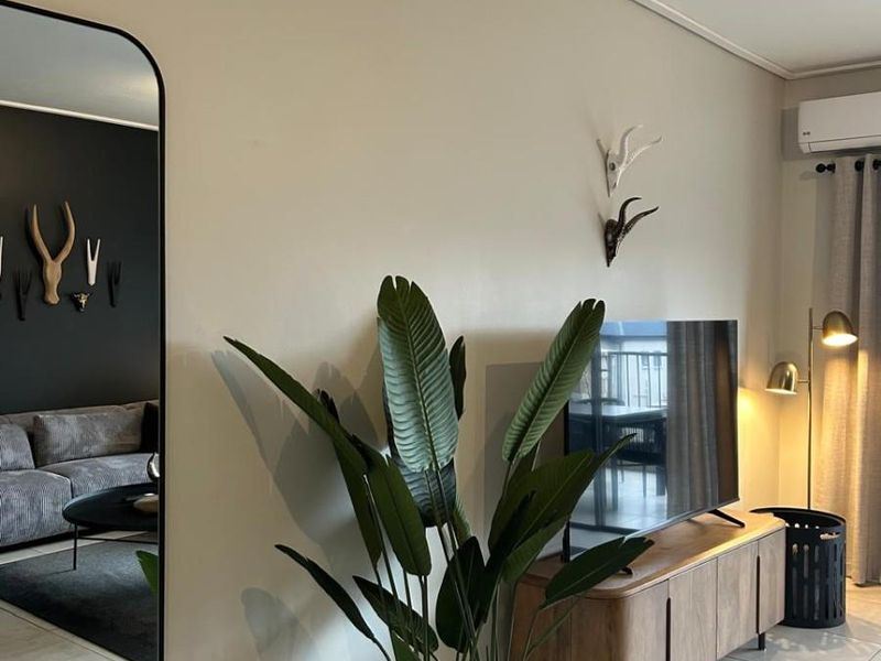 A well-maintained living area featuring neutral tiled flooring, modern skirting boards, and a wall-mounted split-system air conditioning unit.