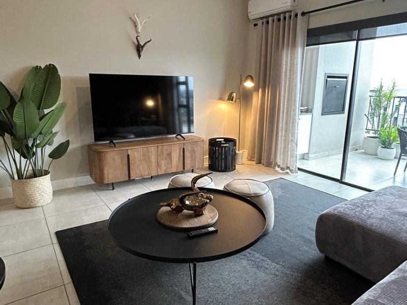 A well-maintained living room featuring tiled flooring, a split-system air conditioner, and large sliding glass doors leading to an outdoor patio area.