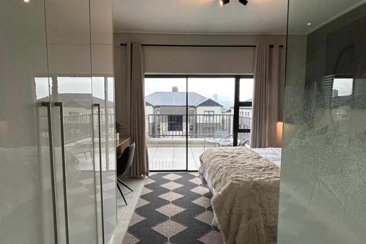 Modern bedroom featuring extensive built-in cupboards, tiled flooring, and large sliding glass doors providing direct access to a private balcony.