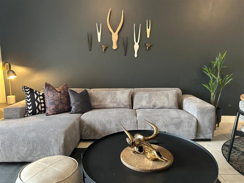 A well-maintained living room featuring a dark accent wall and tiled flooring, creating a modern and inviting atmosphere.