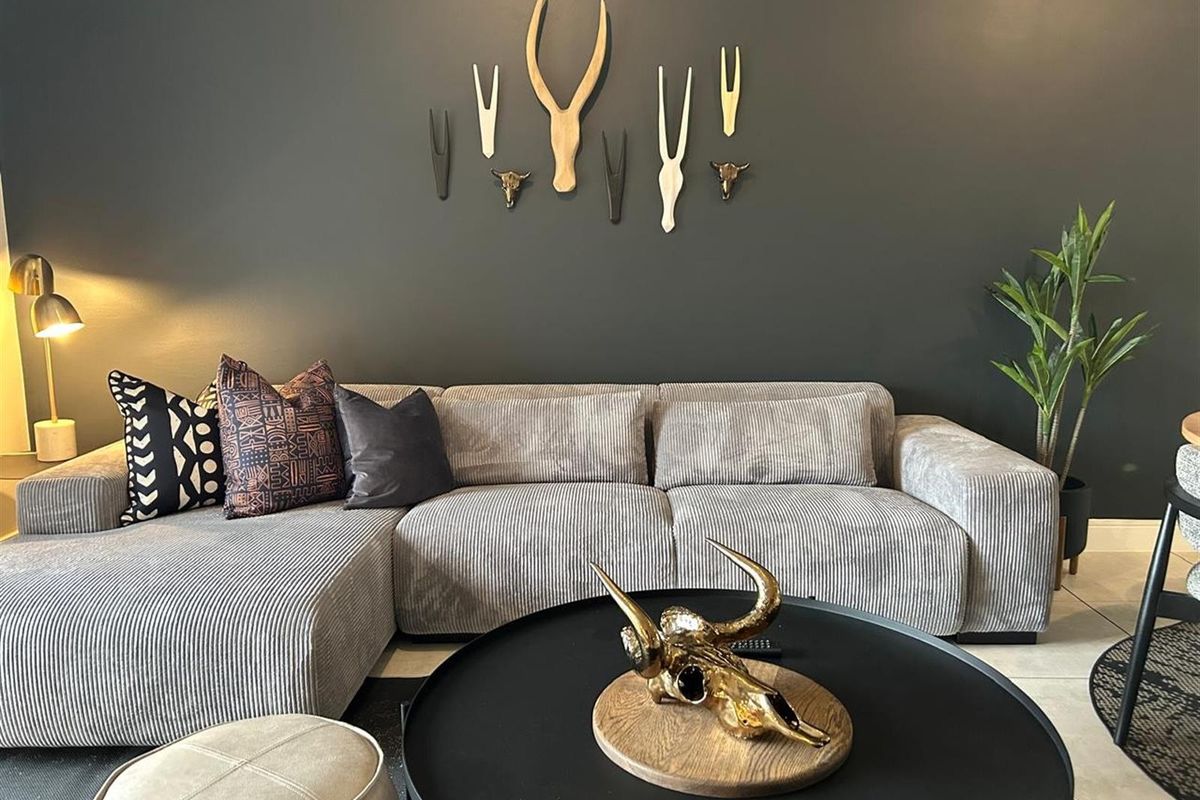 A well-maintained living room featuring a dark accent wall and tiled flooring, creating a modern and inviting atmosphere.