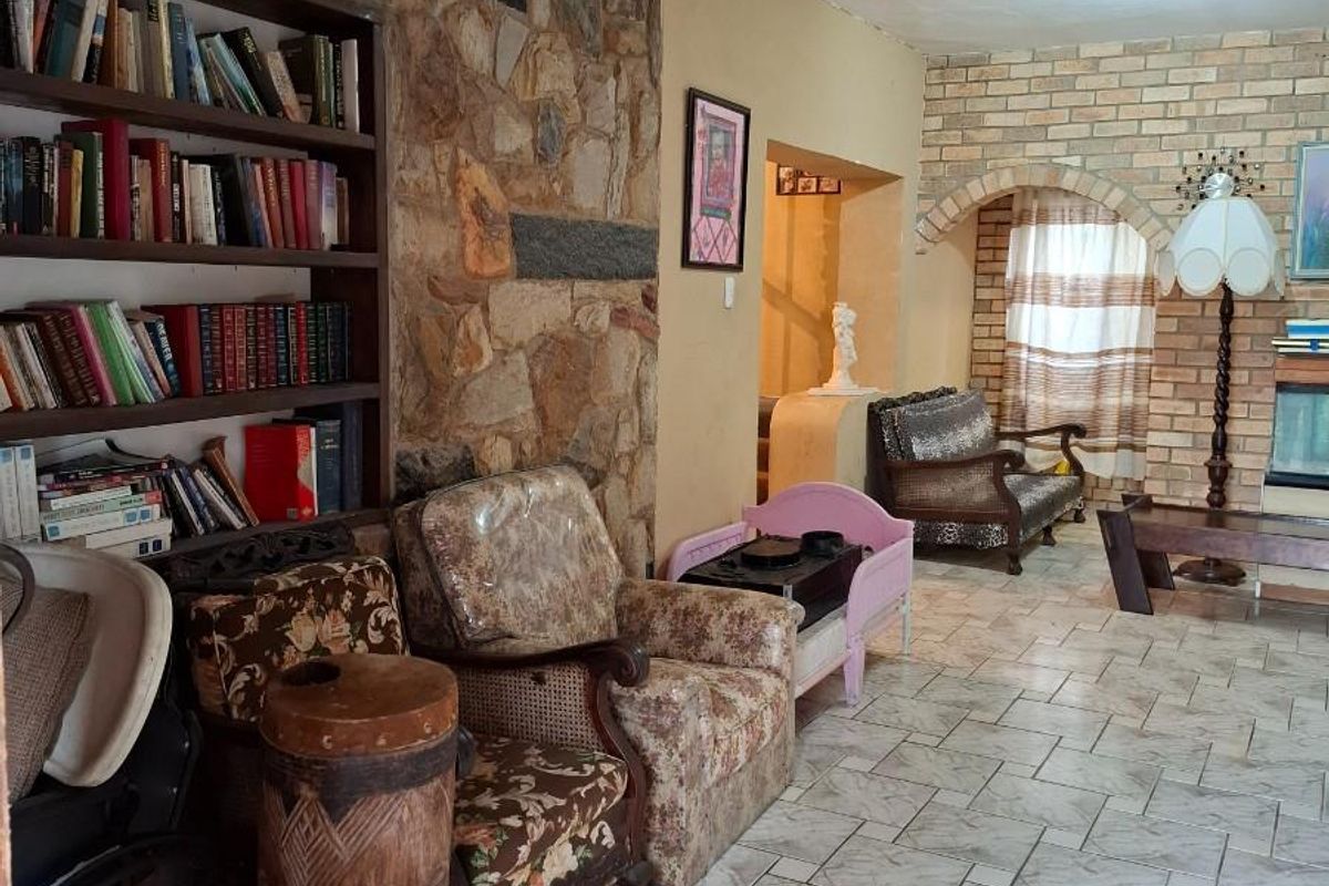 Spacious living area featuring a prominent stone feature wall, built-in shelving, and a brick fireplace surround with classic ceramic tile flooring.