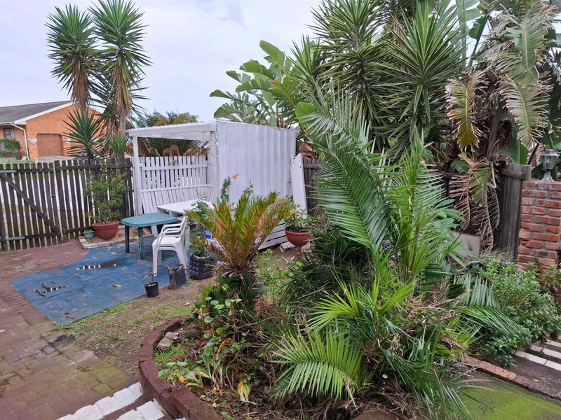 A private garden area featuring established palm trees, brick paving, and a small covered timber structure, offering potential for landscaping improvements.