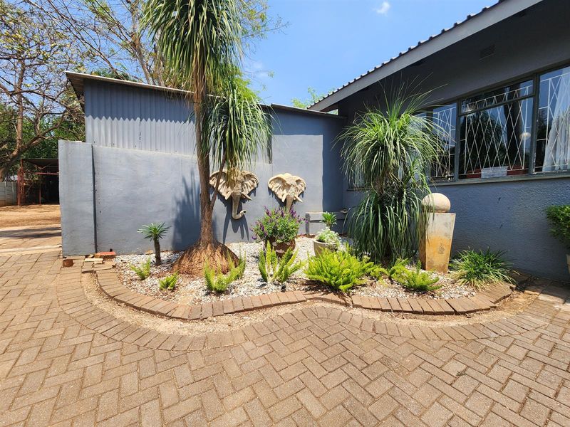 A landscaped rear garden area featuring brick paving, a retaining wall, and security-barred windows on the exterior wall of the house.