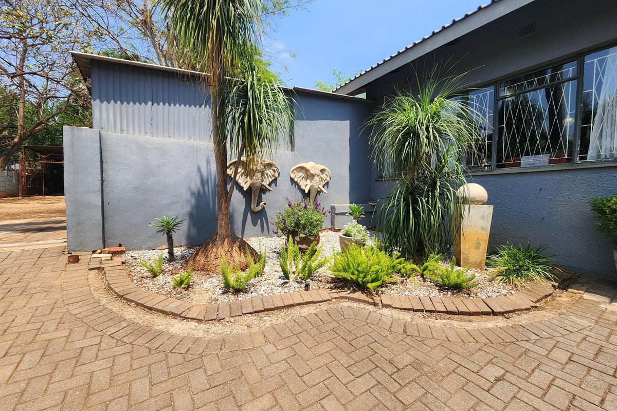 A landscaped rear garden area featuring brick paving, a retaining wall, and security-barred windows on the exterior wall of the house.