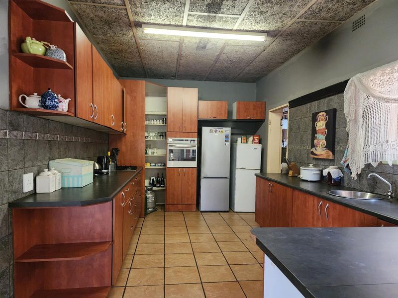 A functional kitchen featuring wood-look cabinetry, laminate countertops, built-in oven, and tiled flooring, offering potential for a modern renovation.