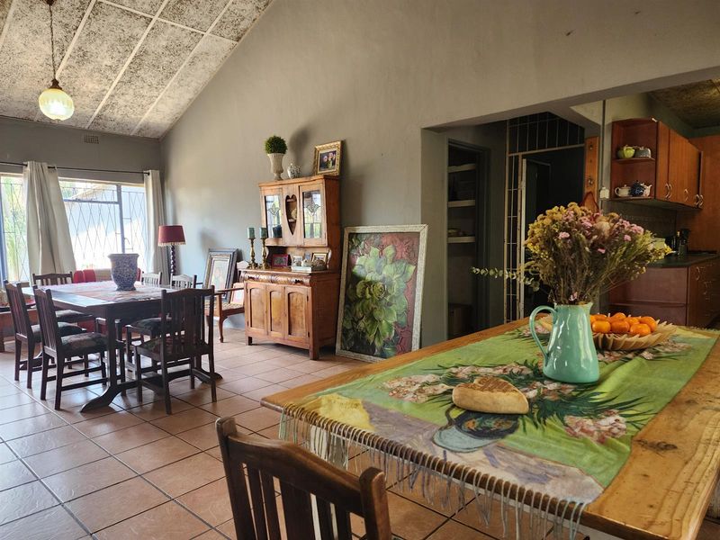 Open-plan living and dining area featuring tiled floors, a vaulted ceiling, and an adjacent kitchen with built-in cabinetry.