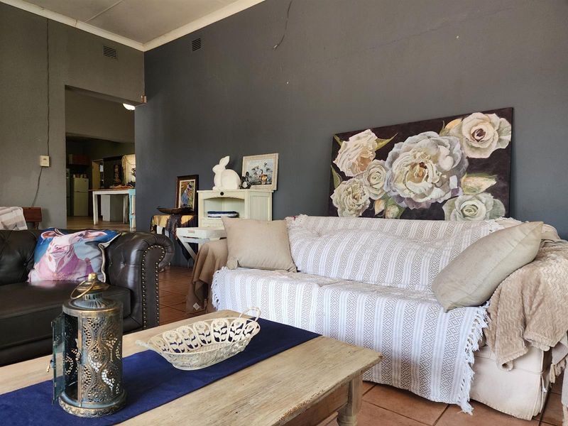Spacious living room featuring tiled flooring and dark grey walls, with an open-plan flow leading into the adjacent kitchen area.